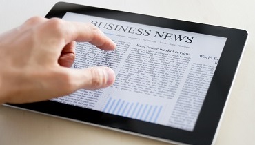 Man hands are pointing on touch screen device with business news.